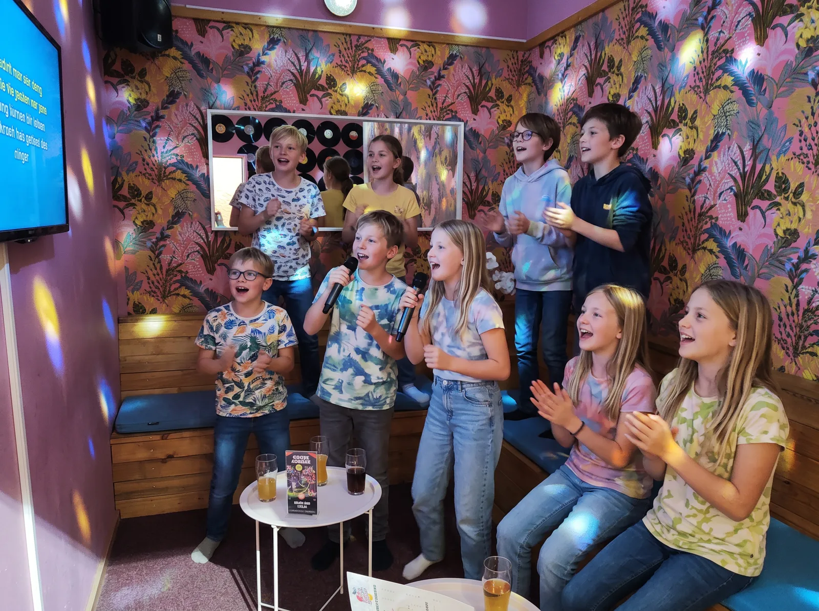 Kinder singen und klatschen im Karaoke-Raum